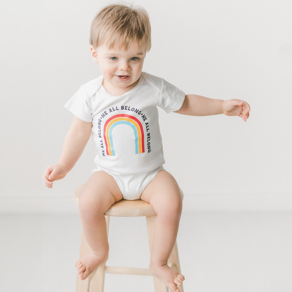 We all Belong Baby Onesie